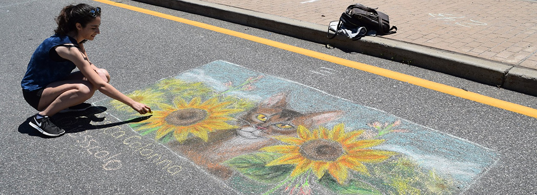People creating chalk art in the street.
